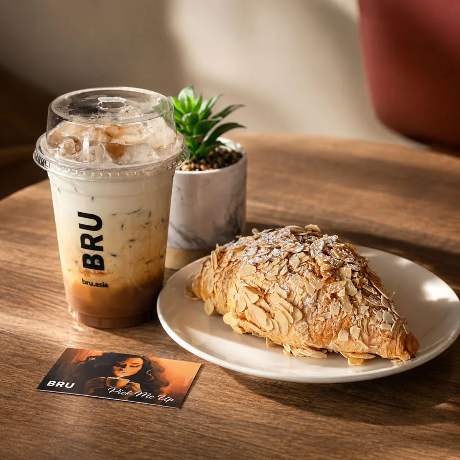 Nutella iced latte and almond croissant on a wooden café table
